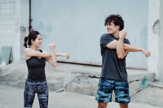 Couple engaging in a warm-up stretch outdoors. Emphasizes health and fitness.